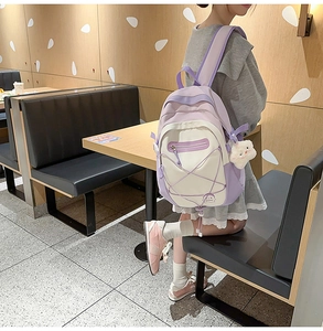 Close-up of a purple and cream canvas backpack with criss-cross ropes and star charm