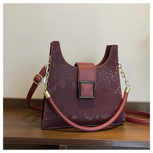 Detail of burgundy snakeskin texture handbag with gold chain strap and metal buckle