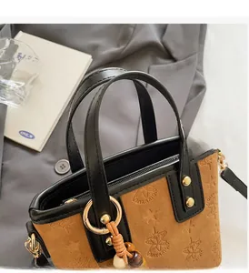 Detailed view of brown suede bucket bag with star patterns and beaded tassel accessory