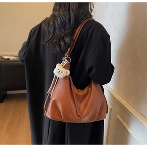 Detailed view of brown PU leather tote bag with soft pleated texture and plush bear charm