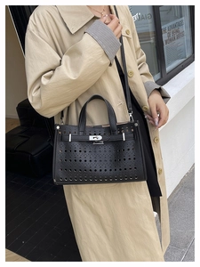 Detail of black laser-cut hollow tote bag with textured leather and classic twist lock