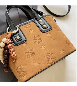 Detail of tan embossed bucket bag featuring star patterns and decorative wooden beads