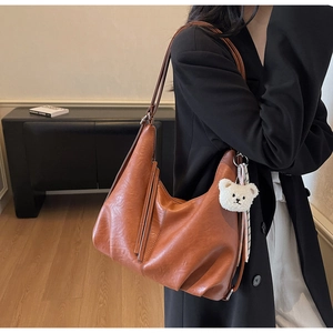 Detail of vintage brown tote bag with plush bear charm and soft matte texture