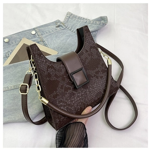 Detail of dark brown faux snake skin texture and gold hardware on a minimalist handbag