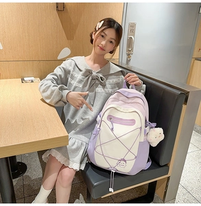 Detail of light purple school backpack with plush pendant in cozy indoor setting