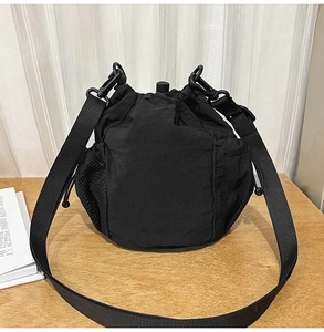 Detail of black nylon bucket bag featuring drawstring closure and side mesh pocket