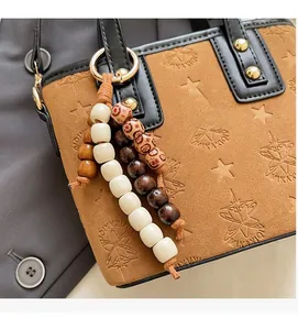 Detail of brown suede handbag featuring star embossing and colorful beaded charms