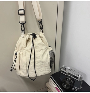Close-up of nylon drawstring bucket bag with black mesh pocket and plastic hardware