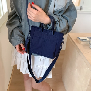 Model wearing a dark blue waterproof nylon mini bag with adjustable shoulder strap