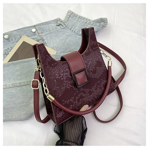 Detailed view of burgundy faux snake skin texture and black resin buckle on a chic handbag