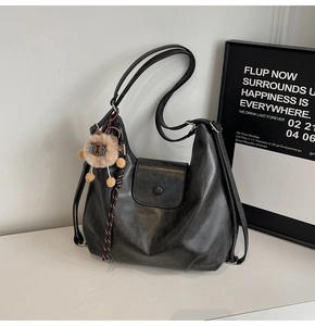 Detail of black faux leather Hobo bag with magnetic flap and brown plush lion charm