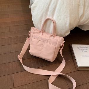 Detail of pink quilted handbag showing soft nylon fabric and adjustable wide shoulder strap