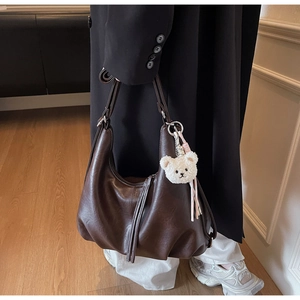 Detail of vintage coffee shoulder bag with pleated bottom and plush bear charm