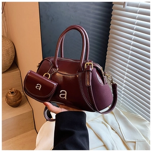 Detail of burgundy boston bag with contrast stitching and hanging small coin purse
