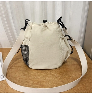 Detail view of beige nylon bucket bag with mesh pocket and drawstring closure