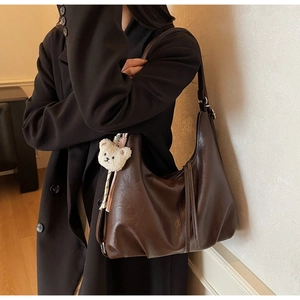 Detail of soft dark brown hobo bag with adjustable strap and cute plush bear charm