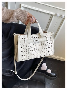 Detailed view of beige laser-cut hollow pattern on a classic tote with metallic buckle