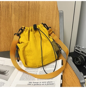 Detail of yellow nylon drawstring bucket bag with mesh pocket on wooden chair