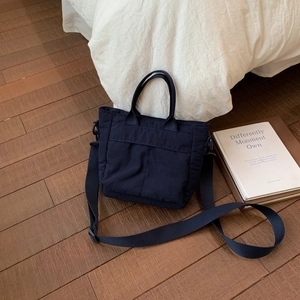 Overhead view of a dark blue nylon tote bag with adjustable strap and sturdy handles