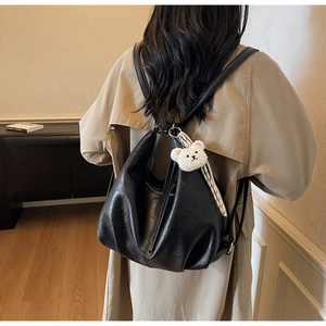 Detail of black soft PU leather backpack with a cute bear plush charm and drawstring design