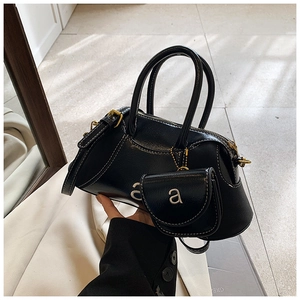 Detail of black glossy handbag featuring silver letter a logo and small coin purse attachment