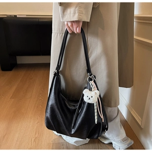 Detail of black large hobo bag featuring soft PU leather and a cute plush bear pendant