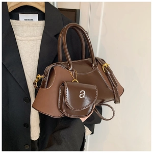 Detail of brown vintage boston bag featuring white stitching and small hanging coin purse