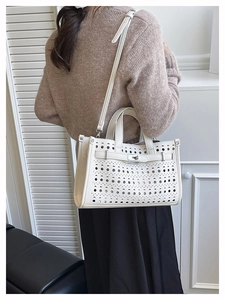 Close-up of white hollow-out leather tote bag with silver twist lock and strap