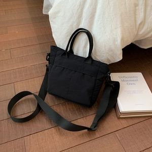 Detail of black canvas tote bag with front pocket design and long shoulder strap