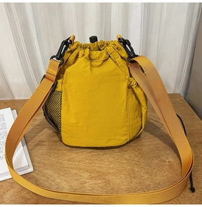 Detail of yellow nylon drawstring bucket bag featuring a side mesh pocket and outdoor style