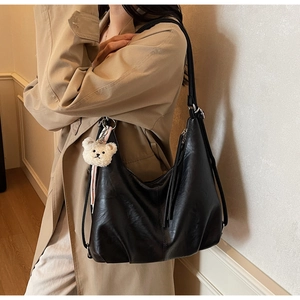 Close-up of black PU leather tote bag featuring subtle texture and a cute bear charm