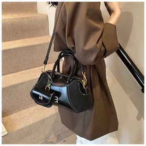 Detail of black glossy leather bowling bag with contrast stitching and small pouch