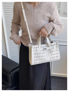 Detailed view of a white cutout tote bag with geometric holes and silver metal lock
