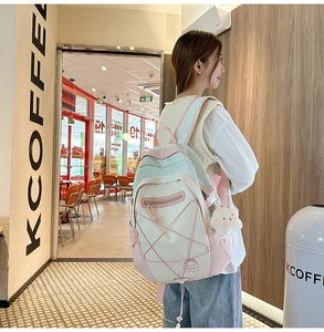 Detail of cute color-block waterproof nylon backpack with plush bear charm accessory