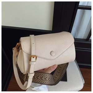Dettaglio borsa beige con doppia tracolla a motivo retrò e fibbia in metallo dorato