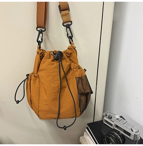 Detail view of brownish-yellow nylon bucket bag with mesh pocket and drawstring closure
