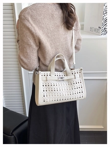 Detailed view of white perforated leather tote featuring silver twist lock and crossbody strap