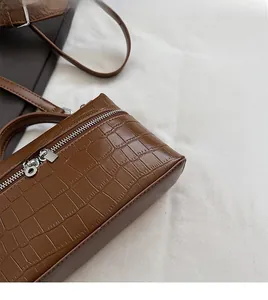 Detail showing deep brown crocodile texture finish and metallic zipper on handbag