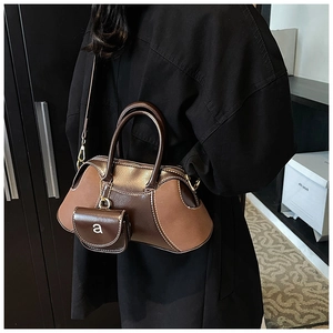 Detail of two-tone brown tote bag featuring textured leather and a mini coin purse charm