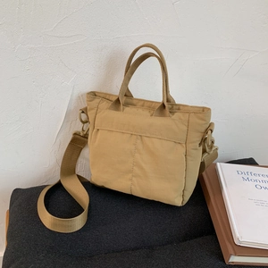 Detailed view of khaki nylon tote bag with wide adjustable strap and vertical stitching