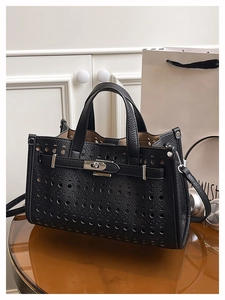 Close-up of black hollow-out lychee leather tote bag with silver twist-lock hardware detail