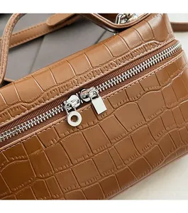 Detail of brown crocodile pattern handbag featuring smooth silver double zippers