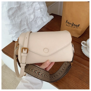 Dettaglio borsa squadrata in pelle crema con tracolla jacquard su base in legno