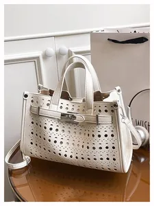 Close-up of laser-cut geometric hollow pattern and silver twist lock on leather tote