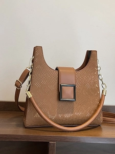 Brown faux snakeskin crossbody bag with golden buckle and chain strap on wood shelf