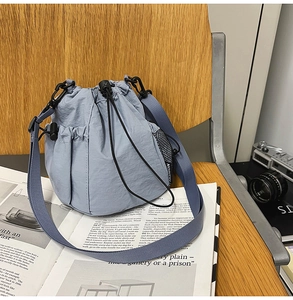 Close-up of light blue nylon drawstring bucket bag with side mesh pocket and wide strap
