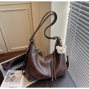 Detailed view of deep brown hobo bag with zipper pull and white plush bear charm