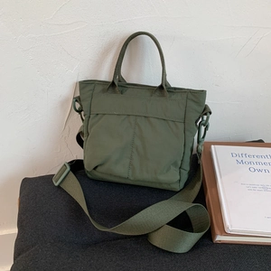 Detail of olive green nylon tote bag with adjustable shoulder strap and decorative stitching