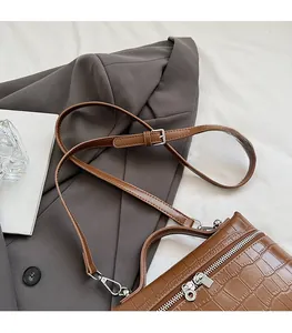 Detail view of brown crocodile texture shoulder bag with silver dual zipper and adjustable strap
