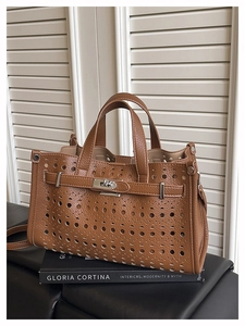 Detailed view of brown hollow-out leather tote with classic buckle and top handles
